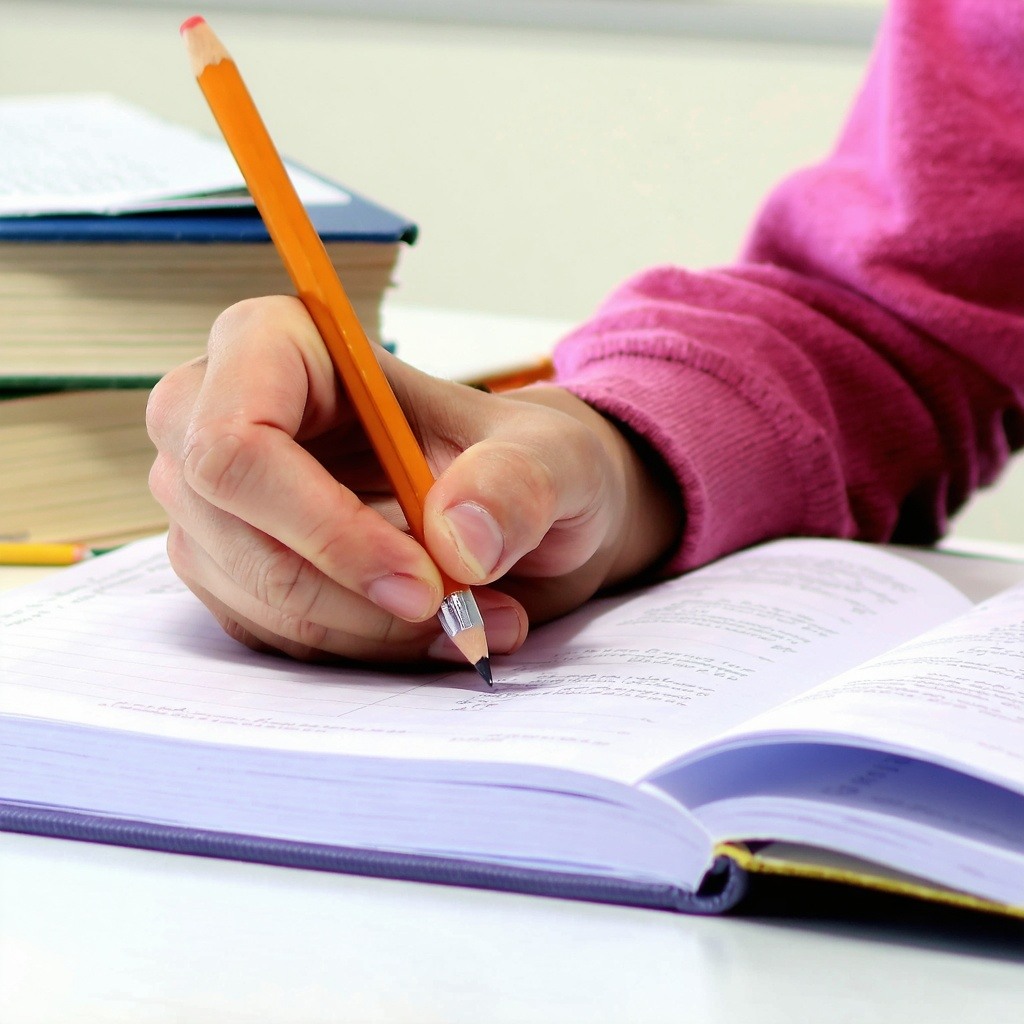 a students hand doing homework